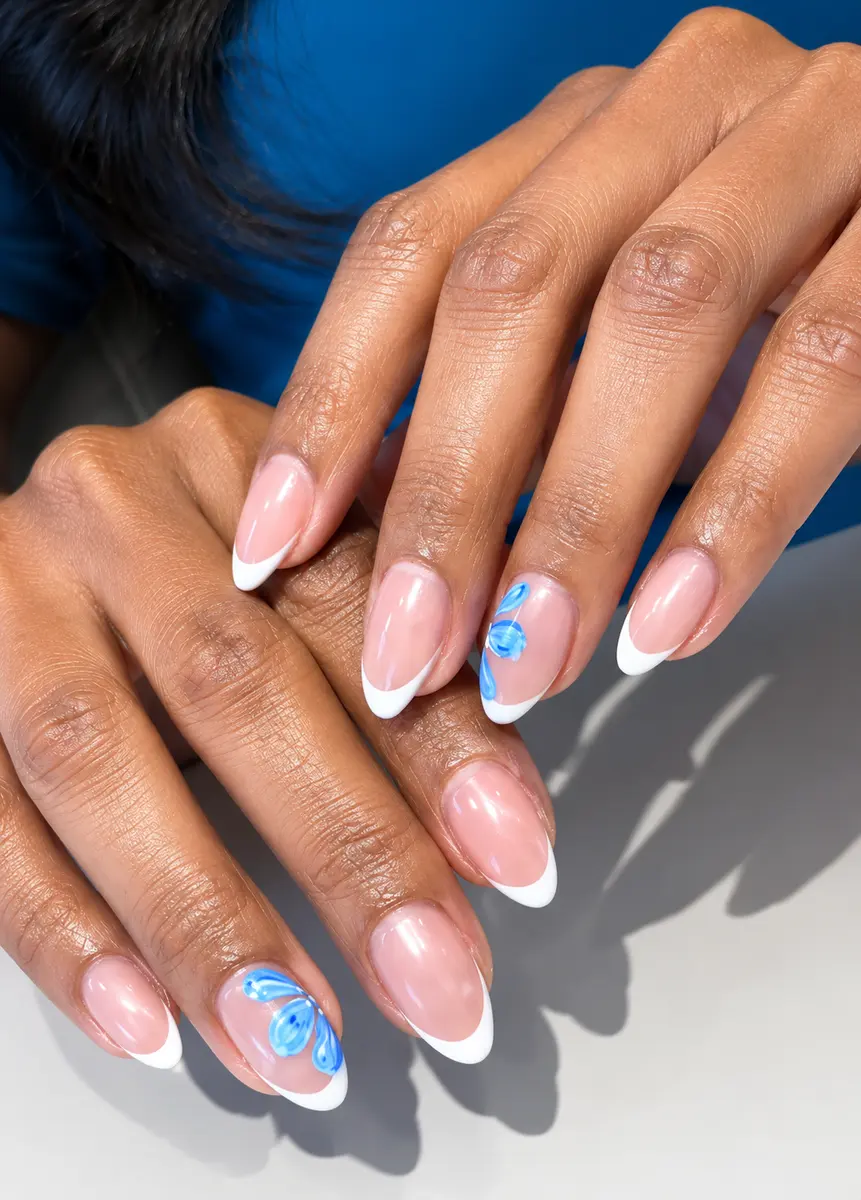 Almond nails with white French tips and a hand-painted blue floral accent