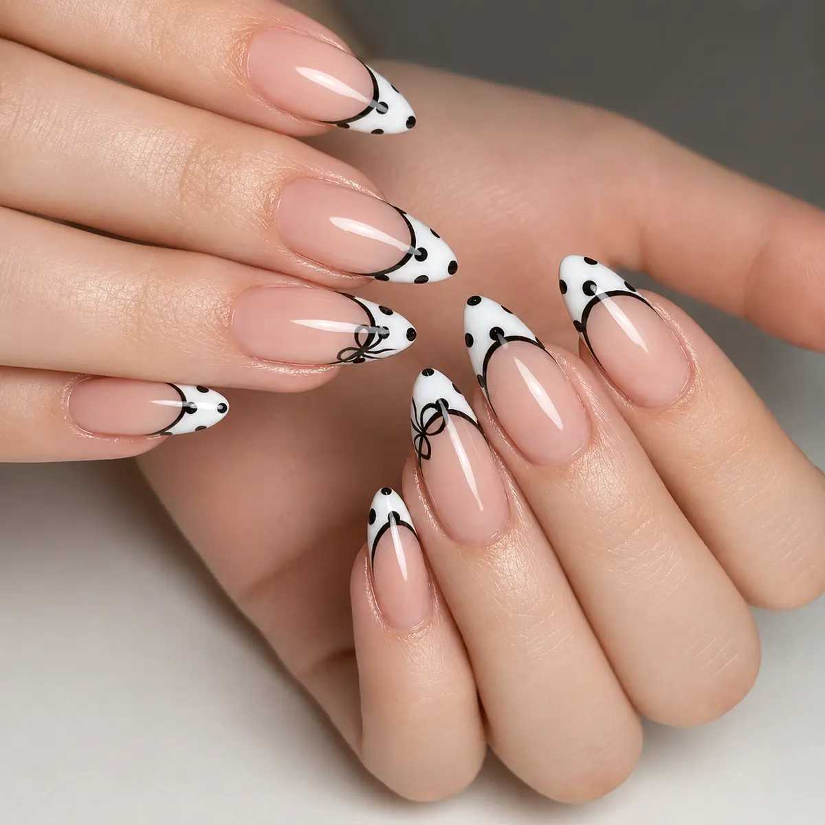 White French tip nails with black polka dots and bow accents
